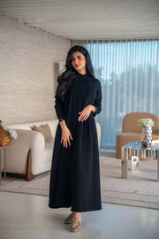 Elegant black crepe abaya with soft, flowing silhouette worn by woman indoors
