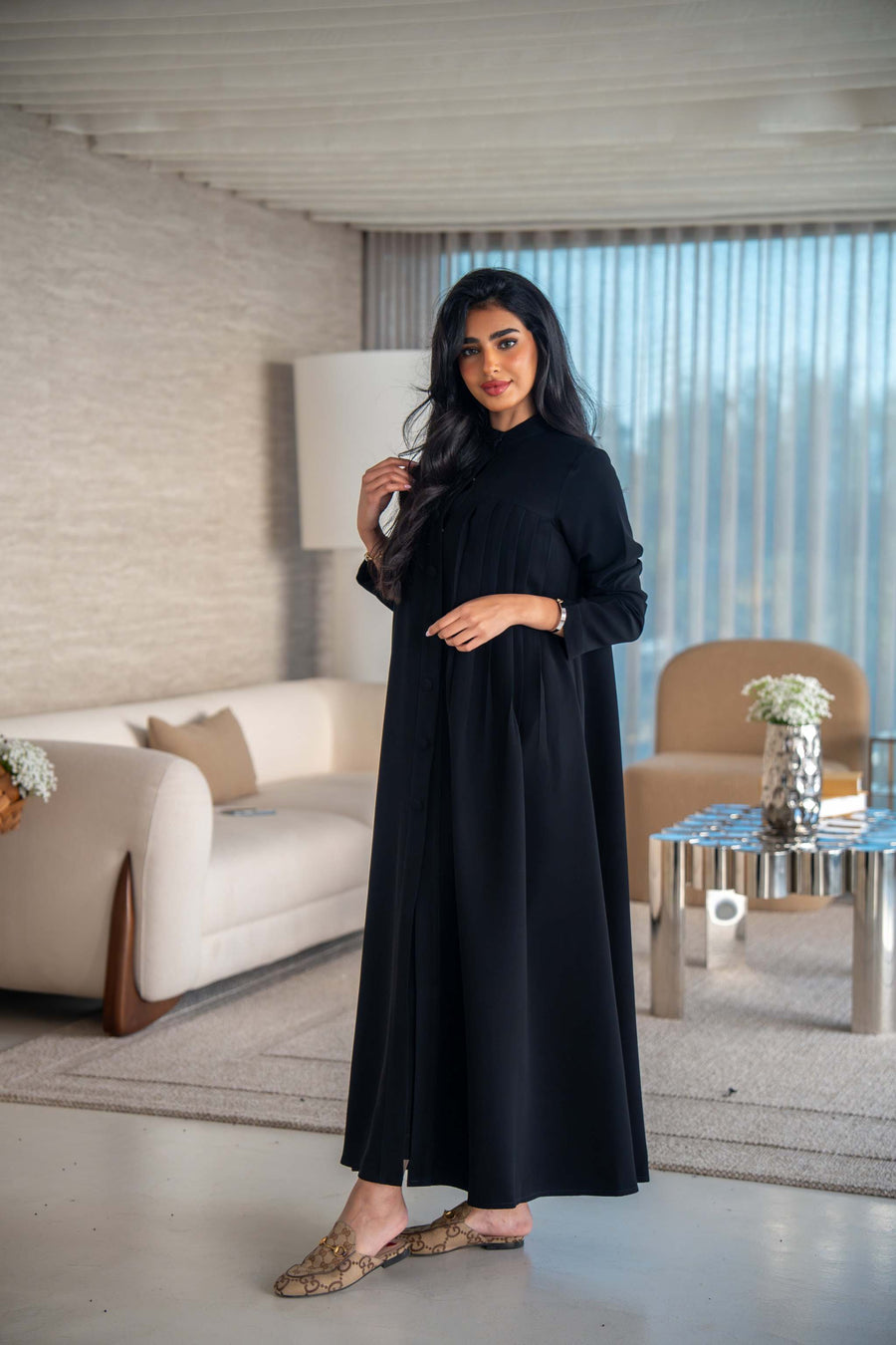 Elegant black crepe abaya with soft, flowing silhouette worn by woman indoors