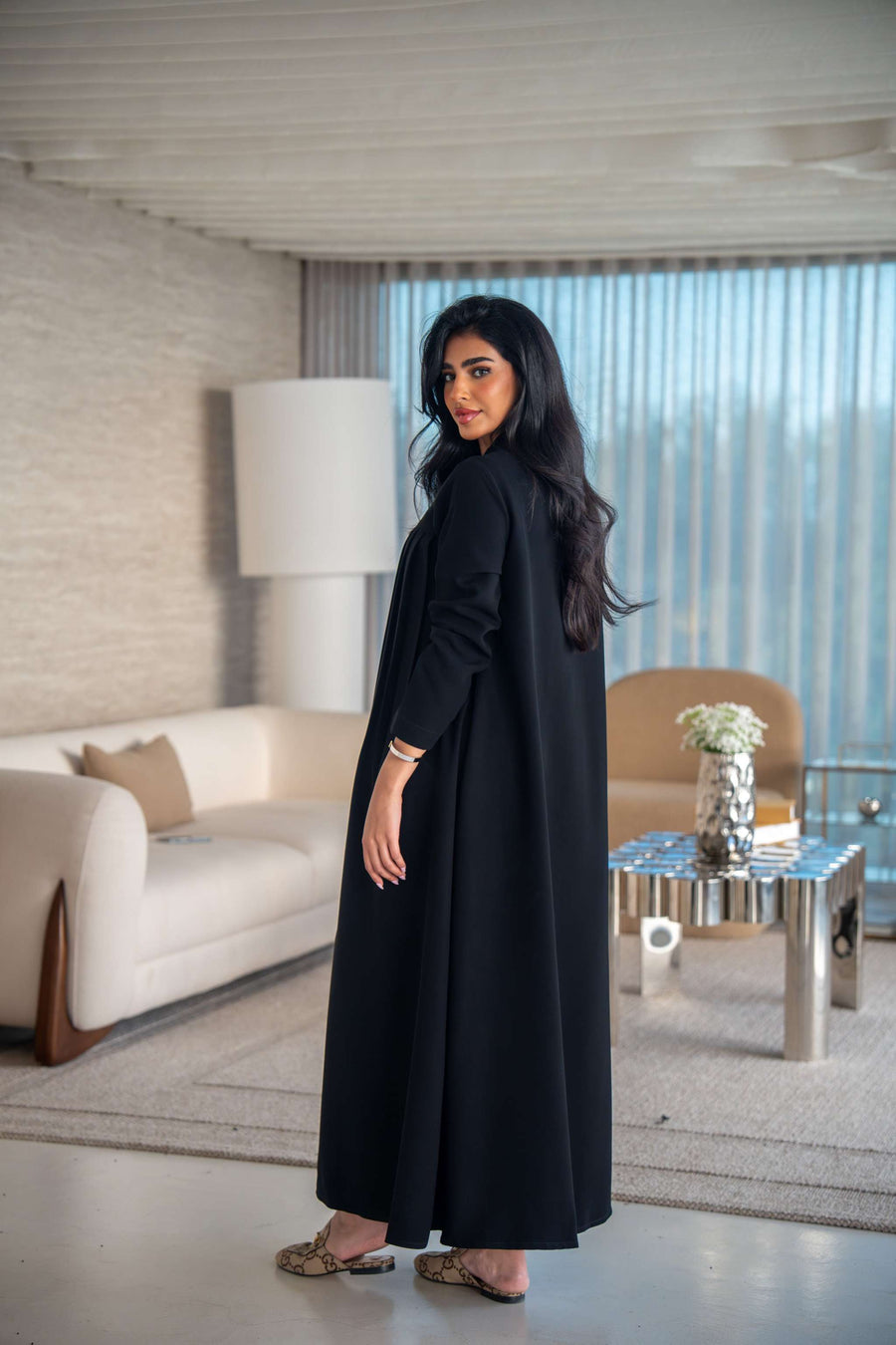Elegant black crepe abaya with soft, flowing silhouette worn by woman indoors