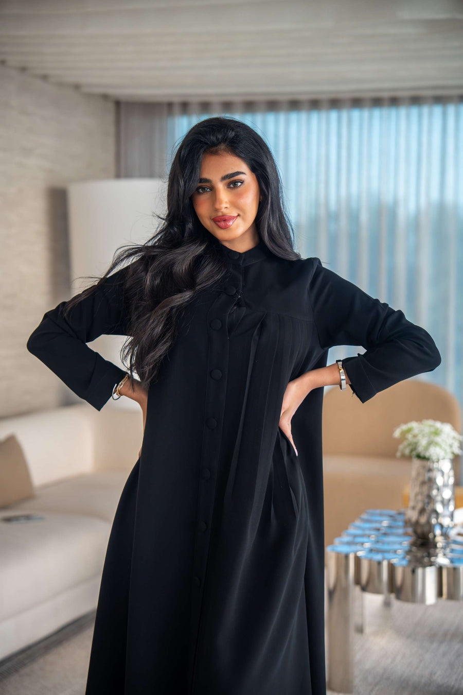 Elegant black crepe abaya with soft, flowing silhouette worn by woman indoors