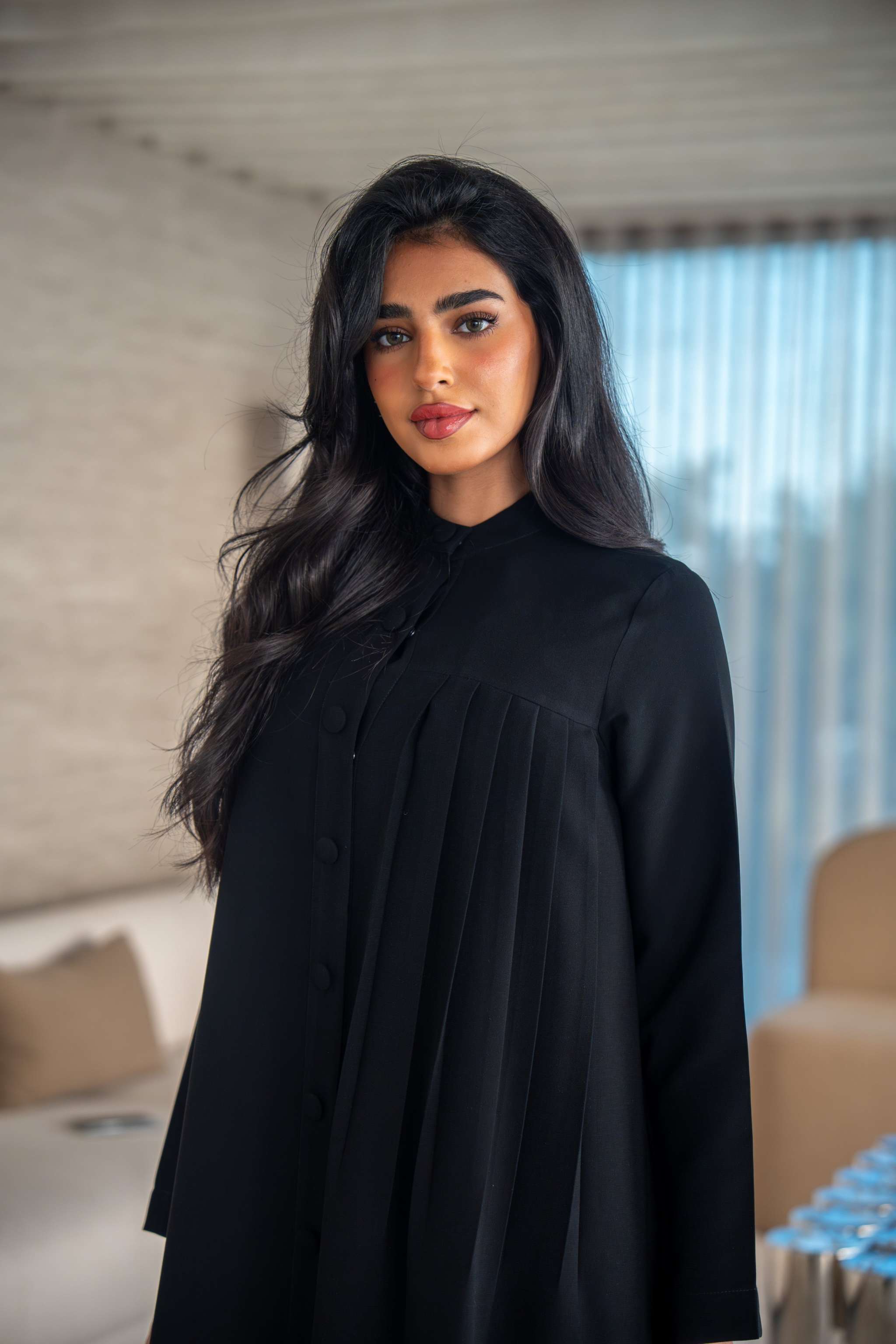 Elegant black crepe abaya with soft, flowing silhouette worn by woman indoors