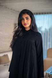 Elegant black crepe abaya with soft, flowing silhouette worn by woman indoors