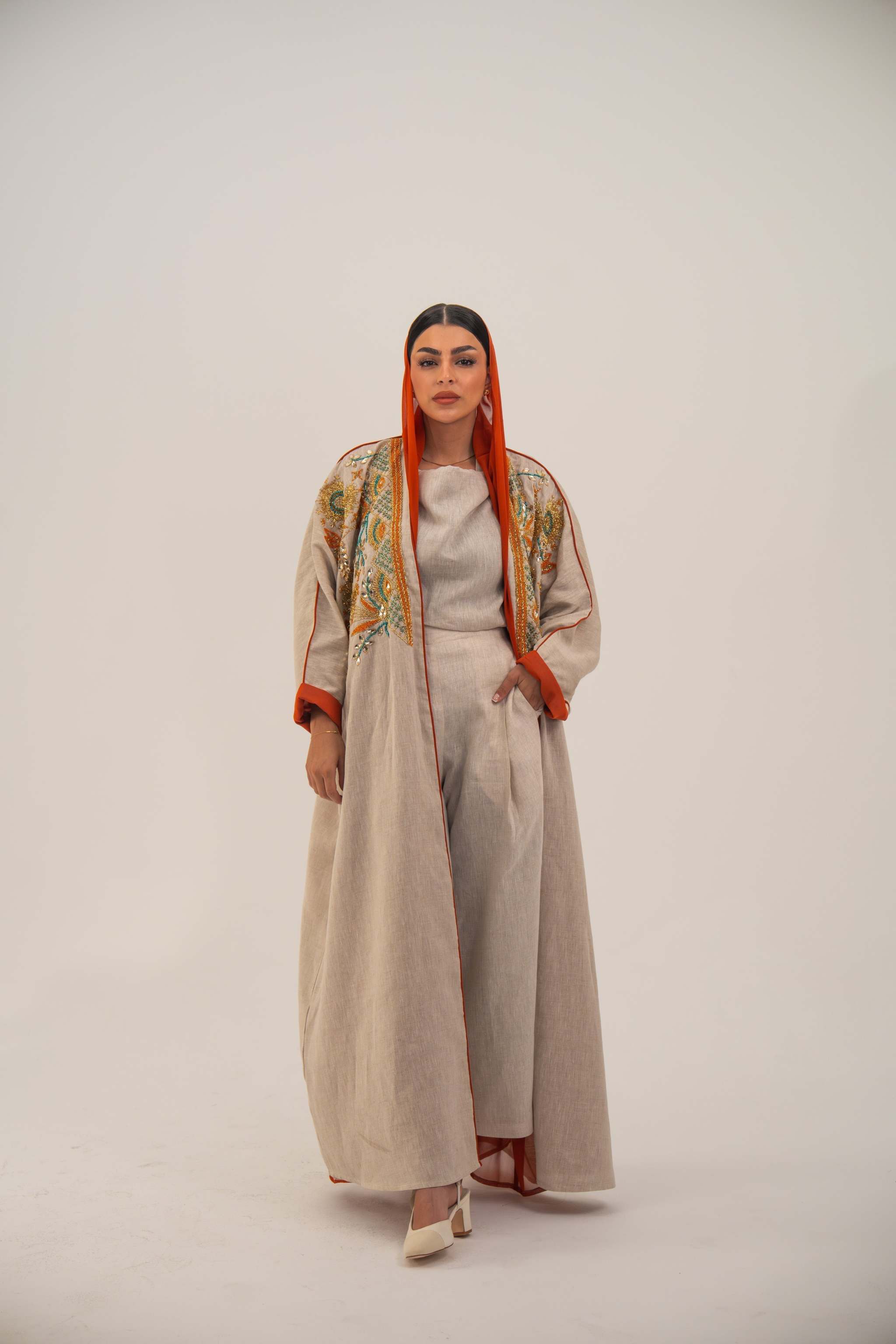 Woman wearing Mango Bisht in neutral linen with mango-orange accents and hand-embroidered shoulders.