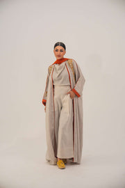 Woman wearing a beige linen-blend abaya with gold and orange beaded embellishments and orange chiffon lining on sleeves and collar