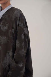 Silk Selva abaya with wide relaxed cut, open front, soft lapel, long sleeves, and subtle dark floral pattern with a soft sheen.