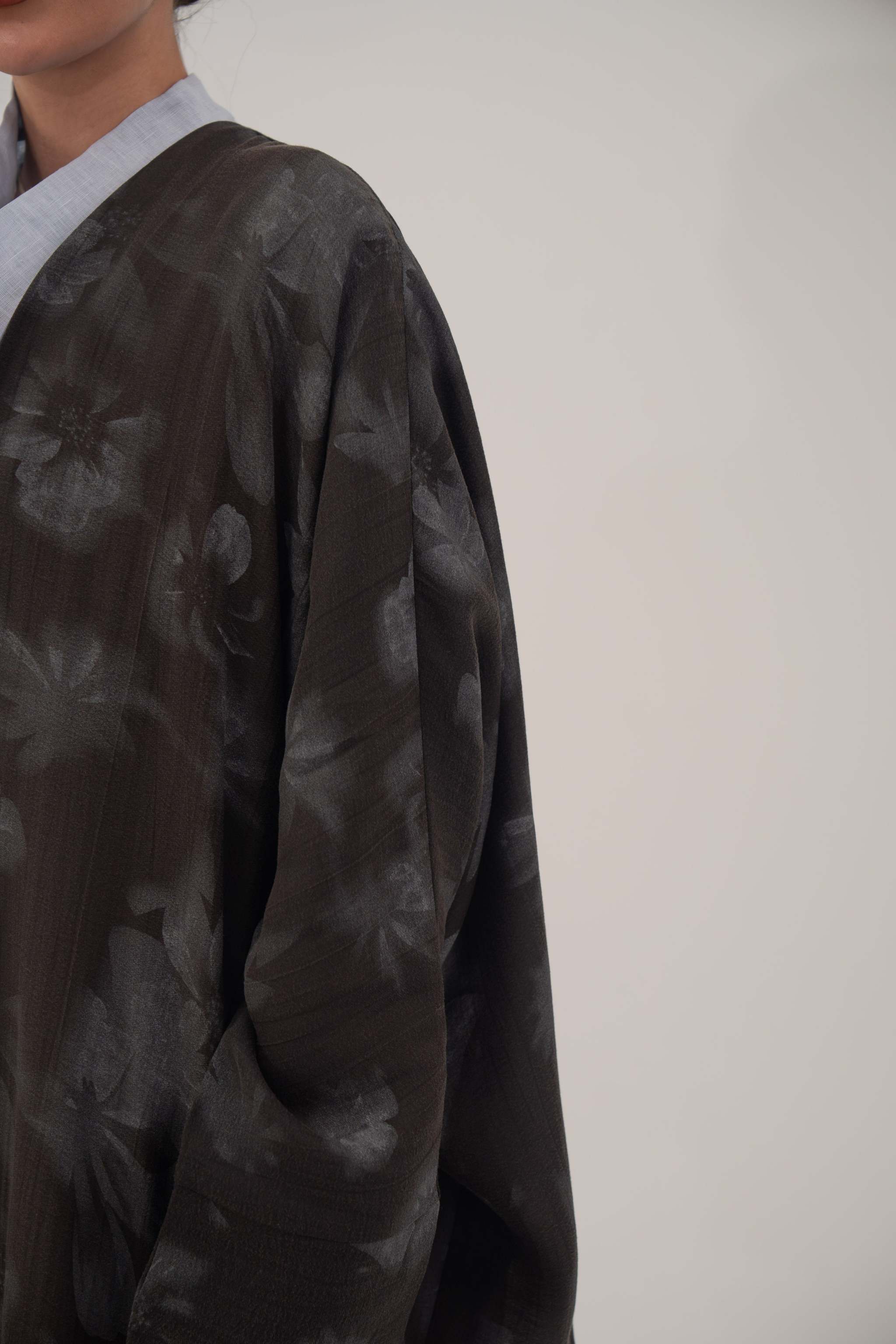 Silk Selva abaya with wide relaxed cut, open front, soft lapel, long sleeves, and subtle dark floral pattern with a soft sheen.