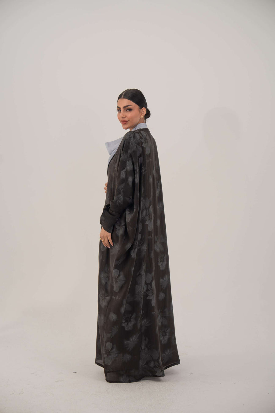 Woman wearing Selva silk abaya with open front, soft lapel, long sleeves, and subtle dark patterned sheen fabric.