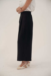 side view of woman wearing black wide-leg silk abaya pants with white top and beige heels