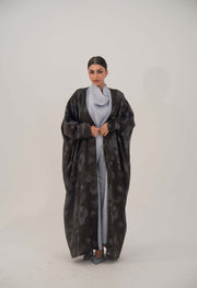 Elegant black silk abaya with relaxed wide cut, subtle floral pattern, open front, soft lapel, and long sleeves.