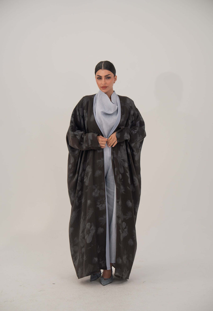 Elegant black silk abaya with relaxed wide cut, subtle floral pattern, open front, soft lapel, and long sleeves.