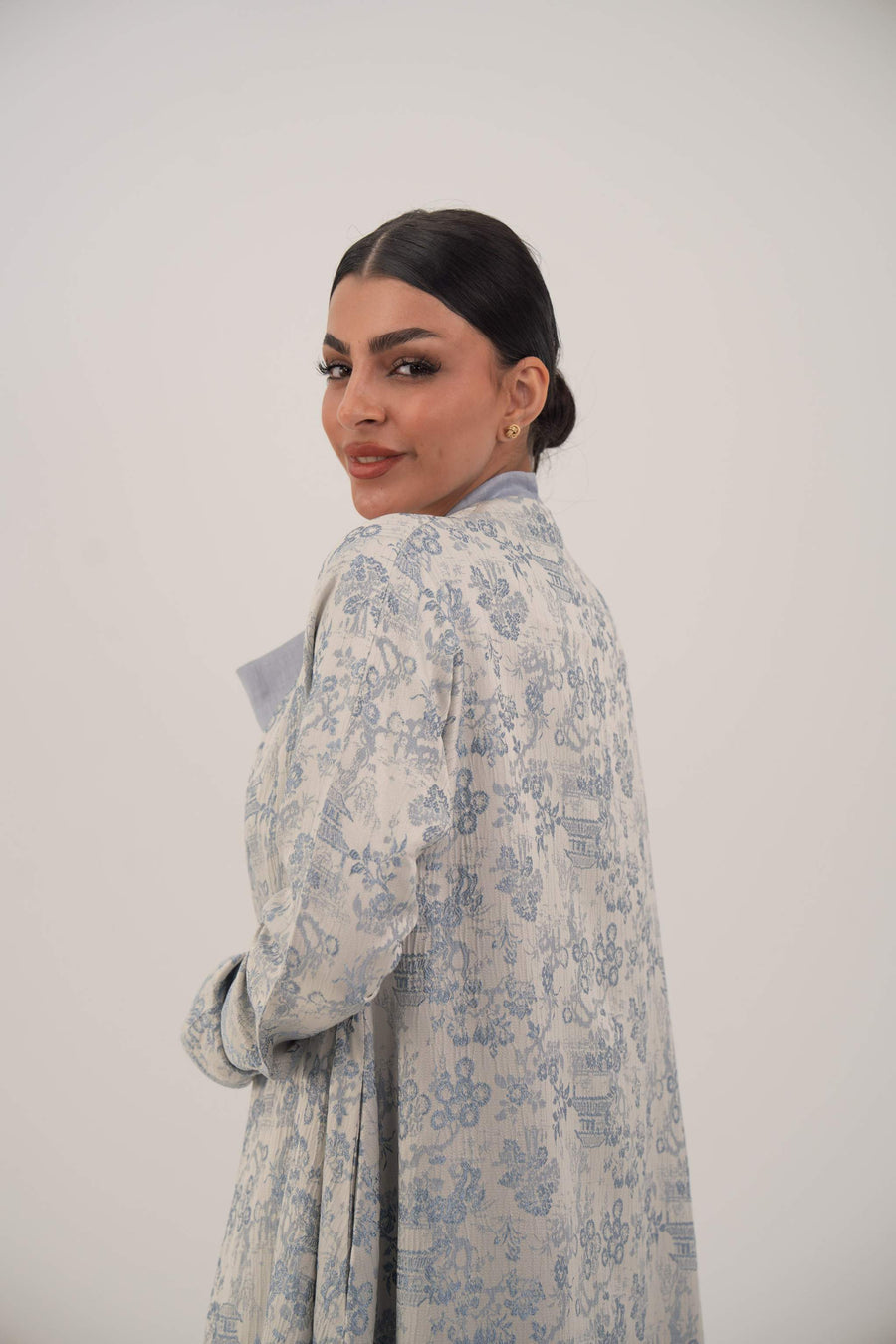 Woman wearing a lightweight jacquard silk open-front abaya with a soft floral pattern and simple lapel design