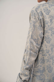 close-up of jacquard silk abaya with soft blue floral pattern on light fabric, featuring long sleeves and elegant texture