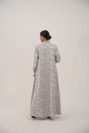 Back view of a woman wearing a long open-front jacquard silk abaya with a soft elegant pattern, simple lapel, and loose sleeves.