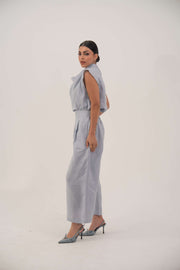 Woman wearing sleeveless light blue linen blouse with relaxed fit and draped collar paired with matching trousers and heels
