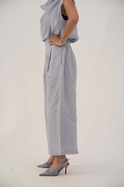 Light blue wide-leg linen pants with high waist and front pleats, cropped above ankle, styled with matching top and heels.