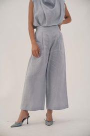Light blue wide-leg linen pants with high waist and front pleats, cropped above ankle for a modern look