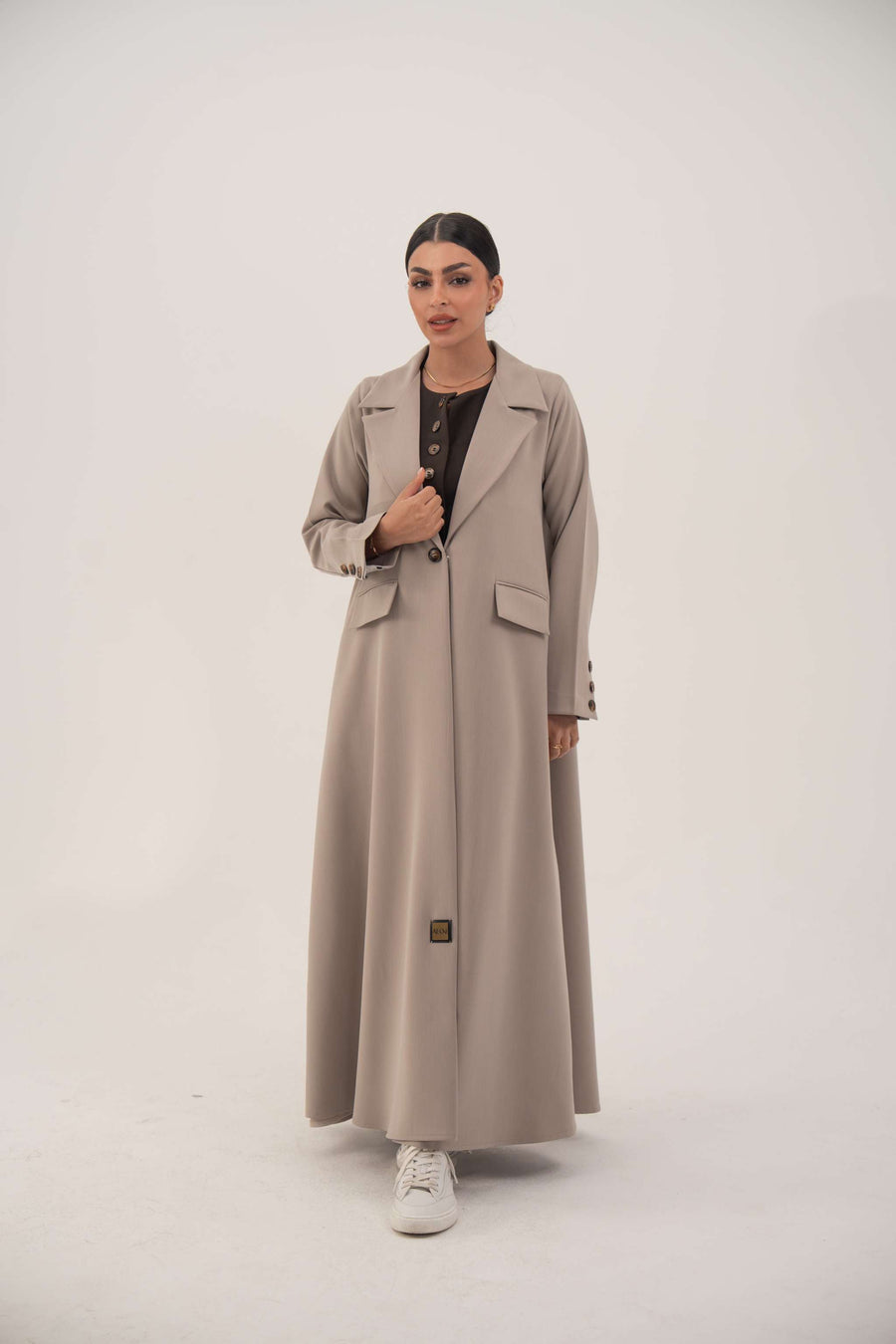 woman wearing light taupe beige blazer with notched collar and single front button standing against white background