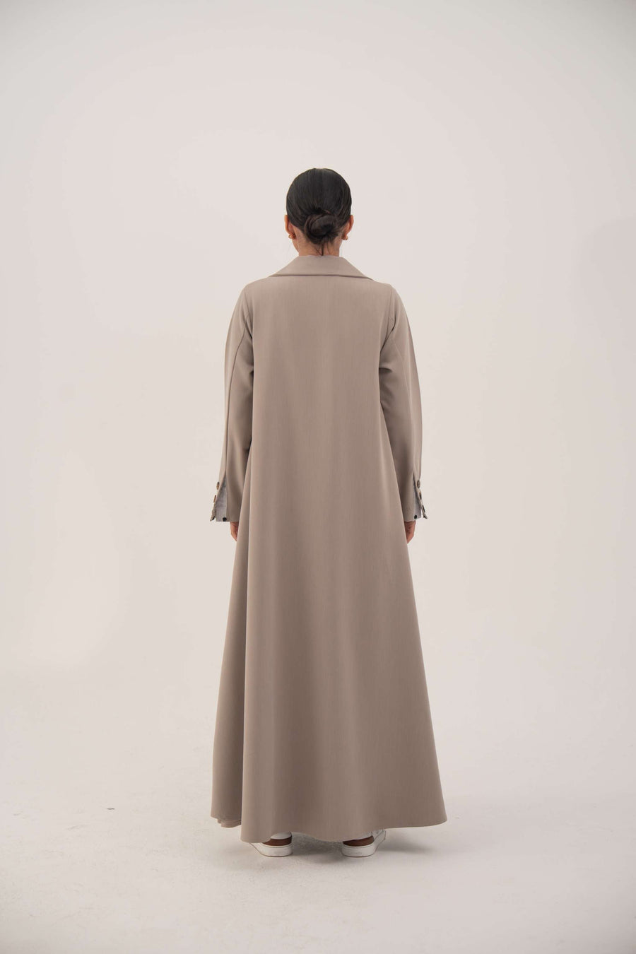 Back view of light taupe beige A-line blazer abaya with notched collar and long sleeves with marbled buttons.