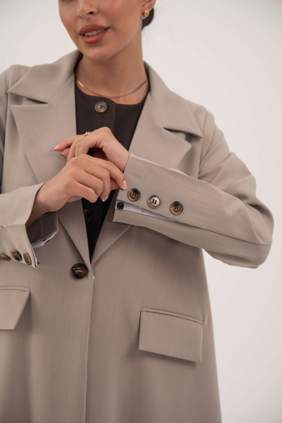 Light taupe beige blazer abaya with notched collar, single front button, brown marbled sleeve buttons, false flap pockets, and A-line cut.