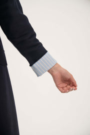Close-up of a deep navy Azura abaya sleeve with folded sky-blue cuffs featuring fine white pinstripes.
