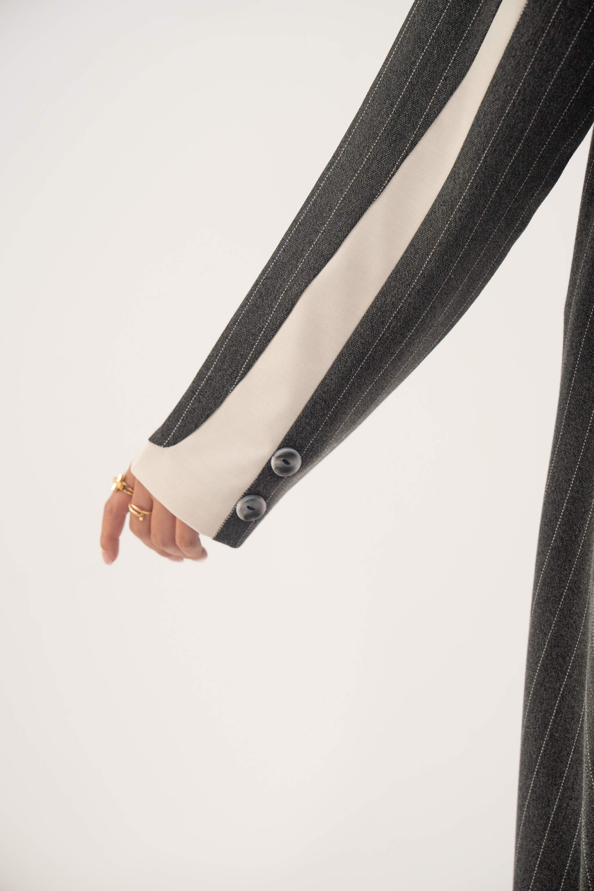 Close-up of Ashmood blazer-style abaya sleeve with white pinstripes, off-white inner cuffs, and button details on crepe fabric.