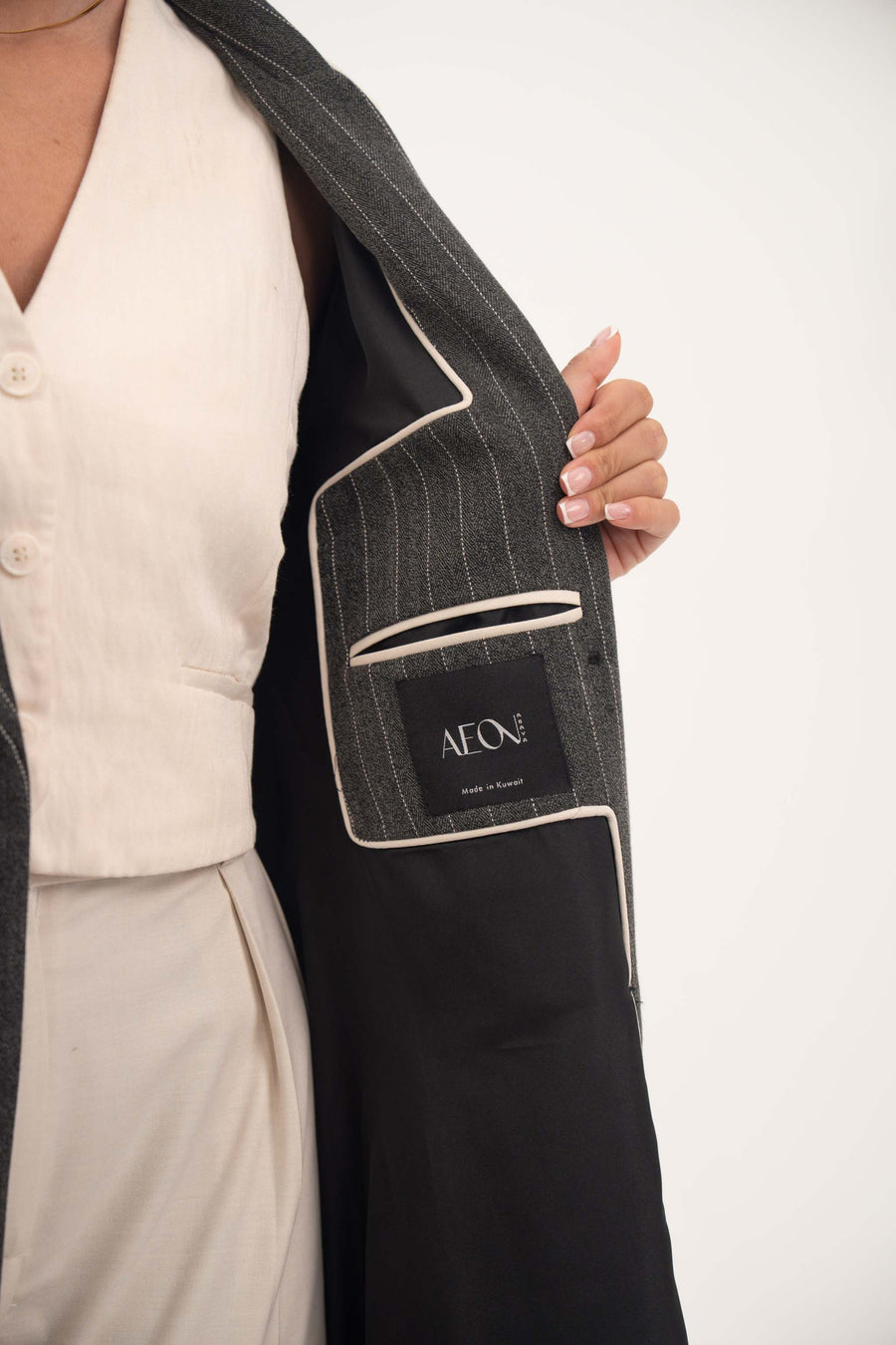 close-up of the inner lining of Ashmood blazer-style abaya showing fine white pinstripes, hidden inner pocket with AEON label, and off-white piping detailing