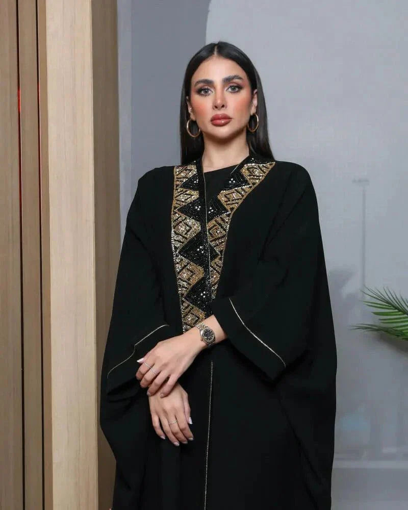 Woman wearing a black bisht with gold and black hand embroidery and a gold brim detail