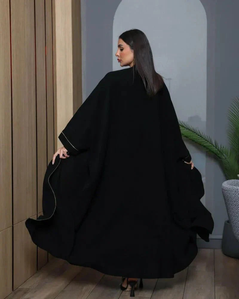 Woman wearing a black bisht with gold and black hand embroidery and a gold brim detail