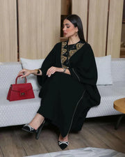 Woman wearing a black bisht with gold and black hand embroidery and a gold brim detail