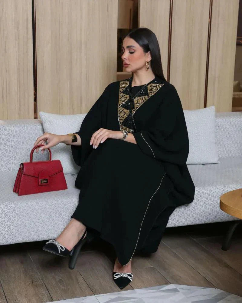 Woman wearing a black bisht with gold and black hand embroidery and a gold brim detail