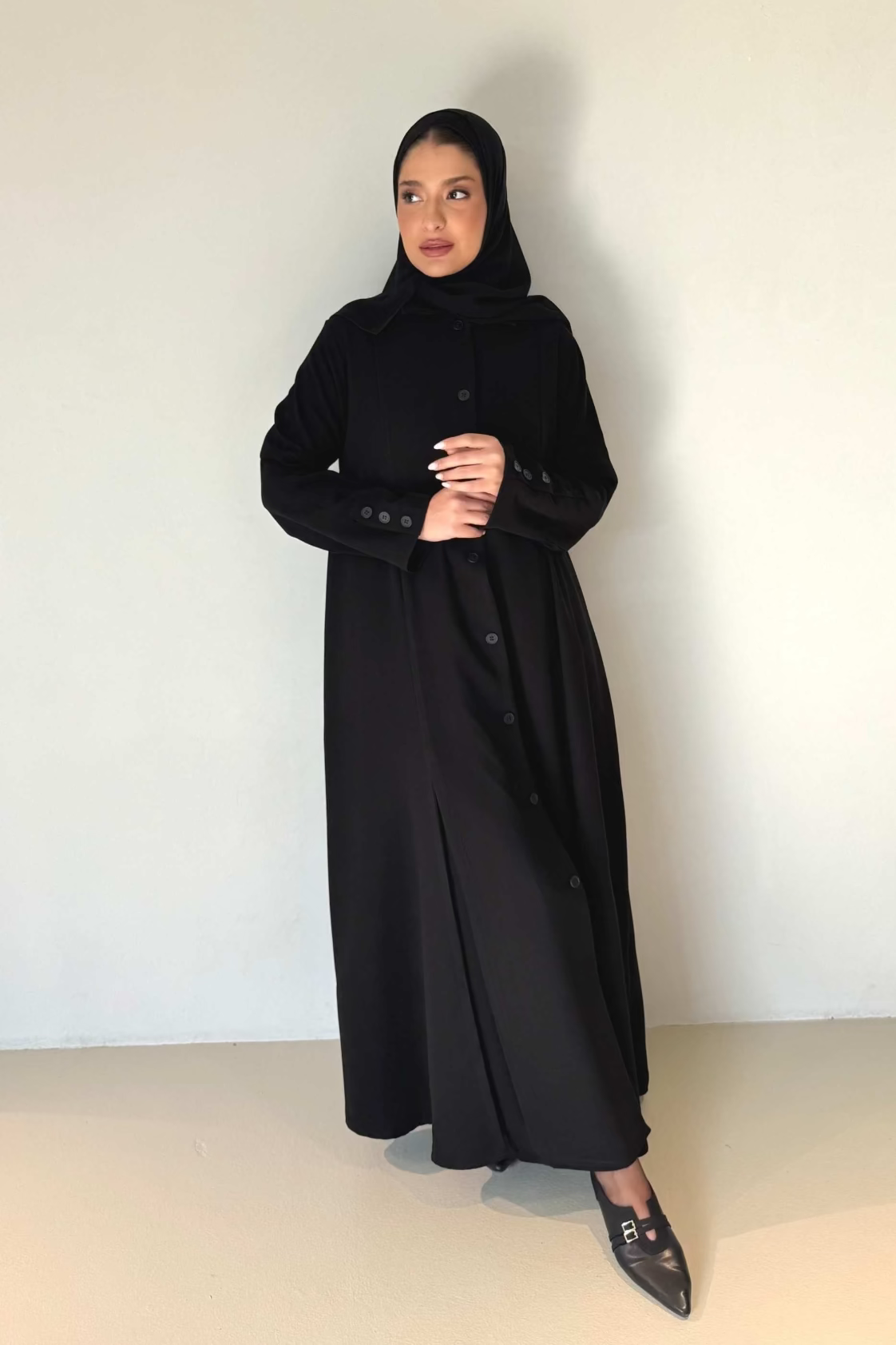 Woman wearing elegant black button-down crepe abaya with tailored fit and subtle flare at hem