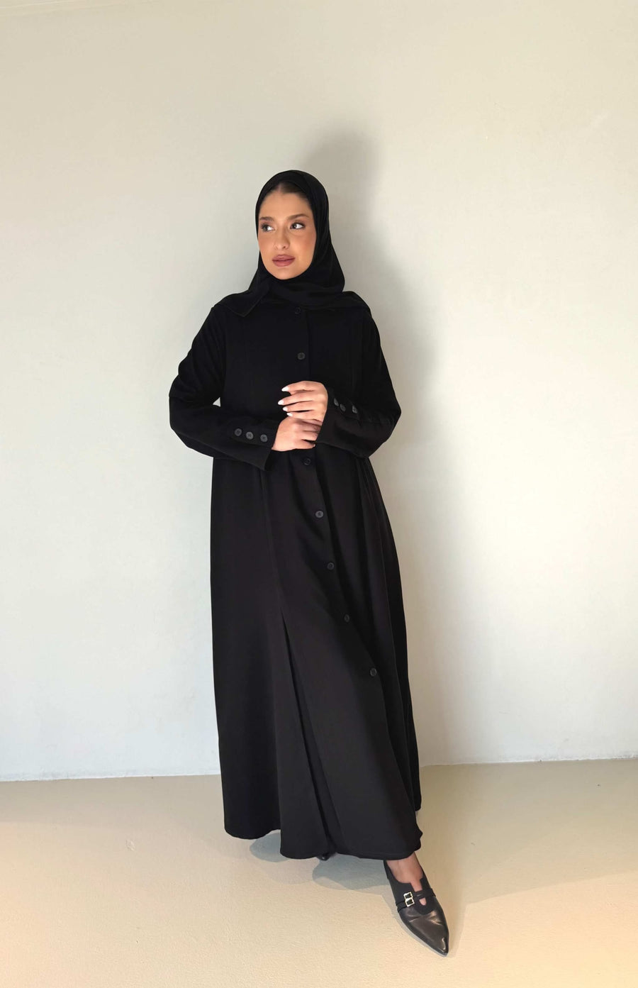 Woman wearing elegant black button-down crepe abaya with tailored fit and subtle flare at hem