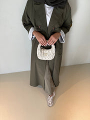 Khaki crepe wide-leg pants styled with a long coat, white top, and sneakers, accessorized with a small white handbag.
