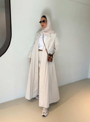 Woman wearing modern everyday beige trenchcoat with minimalist design and flowing lines standing indoors