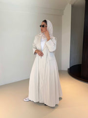 Woman wearing modern everyday beige trenchcoat with minimalist design and flowing lines standing indoors
