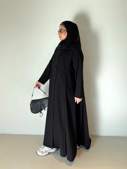 Black flowing crepe abaya with full button-down front, lightweight and elegant, styled with a black hijab and sunglasses.