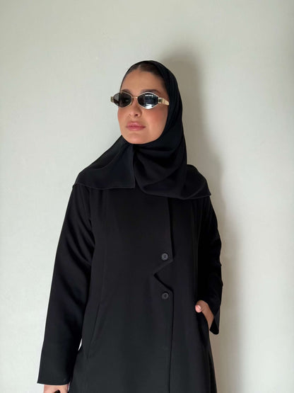 Black flowing crepe abaya with full button-down front, lightweight and elegant, styled with a black hijab and sunglasses.