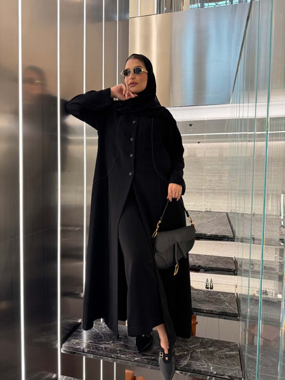 Elegant black crepe abaya with luxurious silk lining and tailored silhouette worn with sunglasses and handbag.