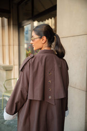 woman wearing chocolate brown trench coat abaya with button-down back and layered detailing outdoors