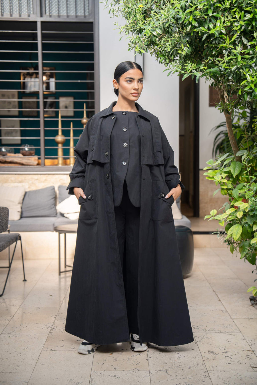 woman wearing long black coat and matching black outfit standing outdoors 832