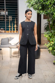 Woman wearing black 809 vest with matching wide-leg pants and sneakers in modern outdoor setting