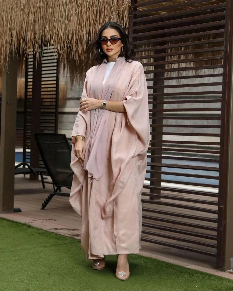 Woman wearing lush soft pink silky bisht with elegant shine flowing outdoors
