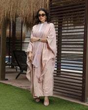 Woman wearing lush soft pink silky bisht with elegant shine flowing outdoors