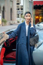Woman in long navy coat holding phone by luxury car with red interior 833