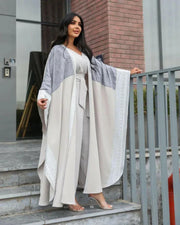 woman wearing light grey bisht with flowy and breathable fabric standing outdoors
