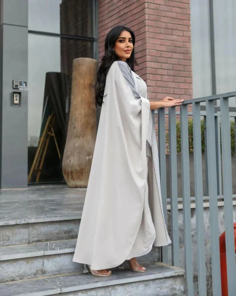 woman wearing light grey bisht with flowy and breathable fabric standing outdoors
