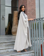 woman wearing light grey bisht with flowy and breathable fabric standing outdoors