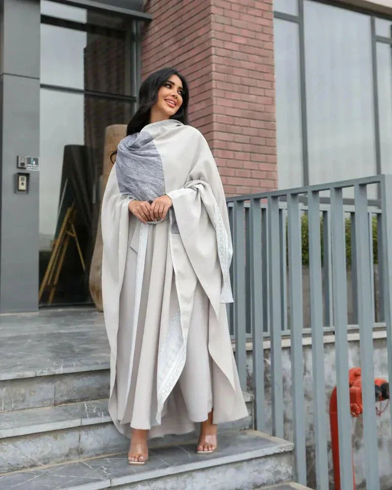 woman wearing light grey bisht with flowy and breathable fabric standing outdoors