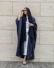 Woman wearing a rich navy abaya in shimmering silk with a classic batwing cut and matching sheila scarf.