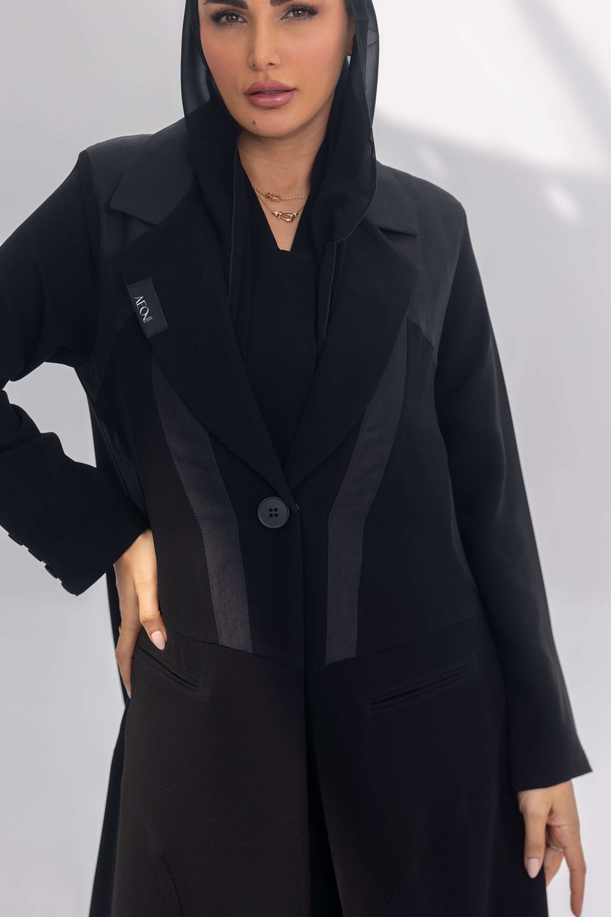 Black crepe abaya with dark grey fabric accents and soft silk lining, front-open design with sleek silhouette.